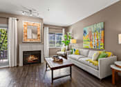 Thumbnail 8 of 12 - A living room with a fireplace and a painting on the wall.