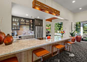 Thumbnail 2 of 12 - A kitchen with a bar area and a refrigerator.