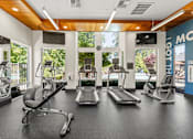 Thumbnail 7 of 12 - A gym with treadmills, elliptical machines, and a weight bench.