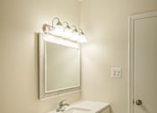 Thumbnail 24 of 31 - A white bathroom with a sink, mirror, and toilet.