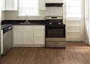 Thumbnail 9 of 31 - A kitchen with white cabinets and black countertops.