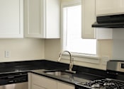 Thumbnail 11 of 31 - A kitchen with a black countertop and a stainless steel dishwasher.