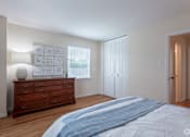 Thumbnail 20 of 31 - A bedroom with a large bed and a dresser with a lamp on it.