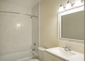 Thumbnail 23 of 31 - A white bathroom with a tub, sink and mirror.