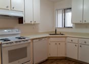 Thumbnail 10 of 22 - an empty kitchen with white cabinets and appliances and a sink at Cowell Terrace Apartments, Concord, 94518