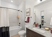 Thumbnail 34 of 40 - A bathroom with a white toilet, a white bathtub, a sink, and a mirror.