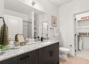 Thumbnail 33 of 40 - A bathroom with a white toilet and a mirror above a counter.