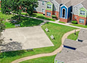 Thumbnail 2 of 23 - A basketball court is surrounded by houses and trees.