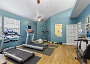 Thumbnail 13 of 38 - A gym with treadmills, elliptical machines, and weights.