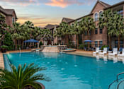 Thumbnail 4 of 27 - A swimming pool surrounded by palm trees and lounge chairs.