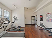 Thumbnail 12 of 23 - A gym with a treadmill, exercise bike and weights.