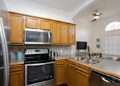 Thumbnail 7 of 13 - a kitchen with a stove sink and microwave and wooden cabinets