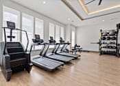 Thumbnail 10 of 40 - A spacious gym with treadmills, elliptical machines, and a rack of dumbbells.