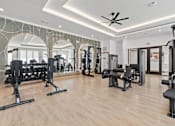 Thumbnail 9 of 40 - A spacious gym with a variety of equipment and a ceiling fan.