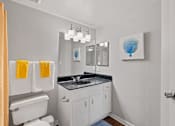 Thumbnail 35 of 38 - A bathroom with a white toilet, sink, and cabinets.