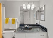 Thumbnail 26 of 38 - A bathroom with a black granite countertop and white fixtures.