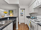 Thumbnail 22 of 38 - A kitchen with white cabinets and black countertops.