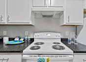 Thumbnail 30 of 38 - A white stove top oven with a blue and white tile backsplash.