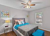 Thumbnail 21 of 38 - A bedroom with a bed, a ceiling fan, and a window.