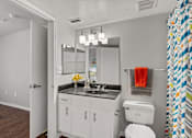 Thumbnail 20 of 38 - A bathroom with a white toilet, a sink with a mirror above it, and a shower curtain with a colorful pattern.