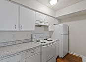 Thumbnail 21 of 23 - A white kitchen with a stove and a refrigerator.