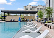 Thumbnail 14 of 19 - A pool with a blue umbrella and chairs.
