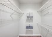 Thumbnail 12 of 20 - a walk in closet with white walls and shelves and two closets