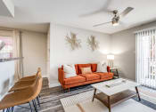 Thumbnail 11 of 20 - a living room with a couch and a table and a ceiling fan