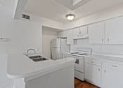 Thumbnail 17 of 23 - A white kitchen with a stove, refrigerator, and sink.