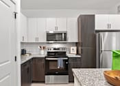 Thumbnail 23 of 40 - A modern kitchen with a stove top oven and microwave above it.