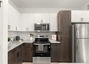 Thumbnail 22 of 40 - A modern kitchen with a stainless steel refrigerator and oven.