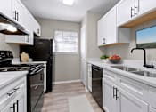 Thumbnail 2 of 16 - an empty kitchen with white cabinets and black appliances and a window
