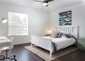 Thumbnail 16 of 18 - A bedroom with a bed, desk, and chair.