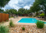 Thumbnail 25 of 37 - a swimming pool in a backyard with rocks and trees