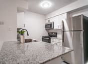 Thumbnail 13 of 37 - a kitchen with a granite counter top and stainless steel refrigerator