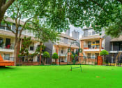 Thumbnail 21 of 37 - a yard with a swing bench and a playground in front of apartment buildings