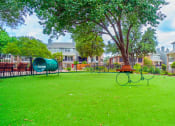 Thumbnail 22 of 37 - a park with a playground and a tree