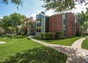 Thumbnail 23 of 23 - a brick building with green grass and trees and a sidewalk
