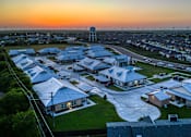Thumbnail 1 of 6 - A sunset view of a residential area with houses and a water tower.