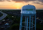 Thumbnail 4 of 6 - A water tower with the word "Portland" on it is in the foreground of a sunset.
