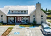 Thumbnail 9 of 9 - A white building with a red door and a parking lot in front.