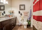 Thumbnail 2 of 9 - A bathroom with a toilet, sink, and a flag hanging on the wall.