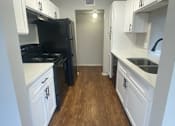 Thumbnail 26 of 33 - a kitchen with white cabinets and black appliances and a wood floor