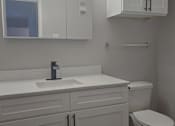 Thumbnail 25 of 33 - a bathroom with white cabinets and a toilet and sink
