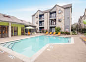 Thumbnail 4 of 18 - A pool surrounded by chairs and umbrellas in front of a building.