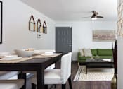 Thumbnail 14 of 18 - A dining room with a table set for two and a green couch.