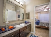 Thumbnail 6 of 25 - a bathroom with a sink and a mirror and a bedroom