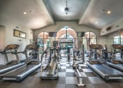 Thumbnail 11 of 25 - a gym with cardio machines and weights on a checkered floor