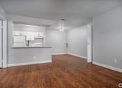 Thumbnail 12 of 35 - the living room and kitchen of an apartment with wood flooring and white cabinets