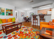 Thumbnail 2 of 35 - a living room with a colorful rug and a kitchen with a table and chairs